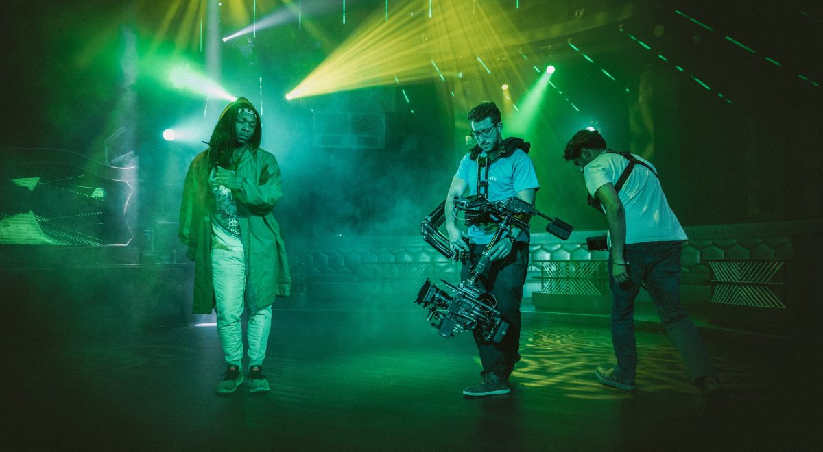 Video shoot with woman dancing under green and yellow lights with fog